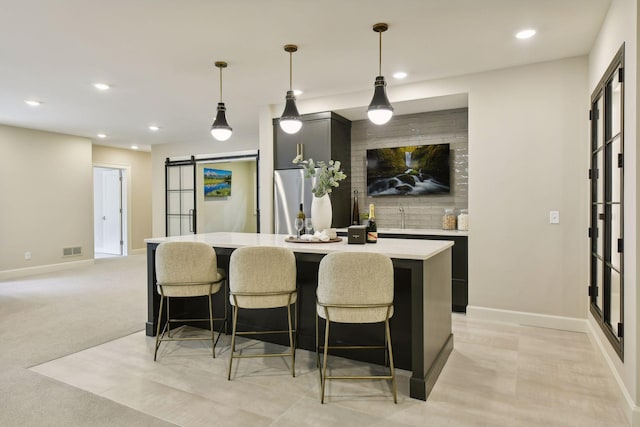 kitchen with visible vents, a center island, a breakfast bar, light countertops, and a barn door