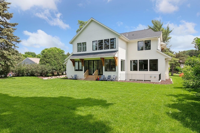 back of property with entry steps, a yard, and a shingled roof