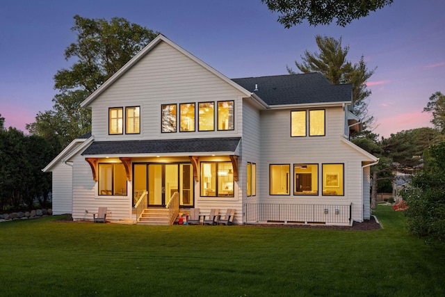 rear view of property with a shingled roof and a yard