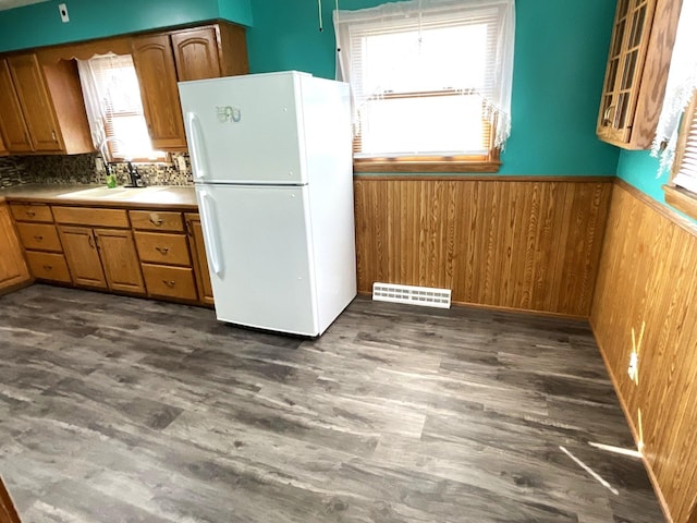 kitchen with wooden walls, visible vents, freestanding refrigerator, a sink, and wainscoting