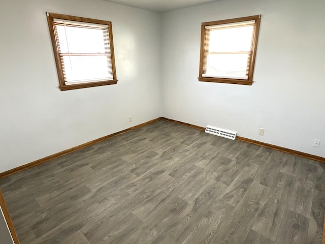 empty room with visible vents, baseboards, and wood finished floors