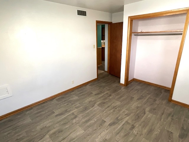 unfurnished bedroom with wood finished floors, visible vents, a closet, and baseboards