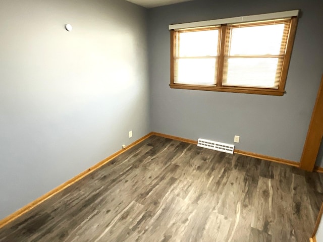 unfurnished room with visible vents, baseboards, and wood finished floors