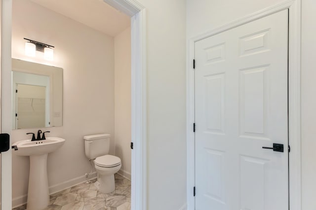 half bath featuring toilet, baseboards, marble finish floor, and a sink