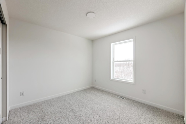 empty room with baseboards, visible vents, and carpet floors