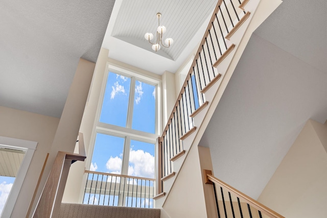 staircase with a high ceiling and a notable chandelier