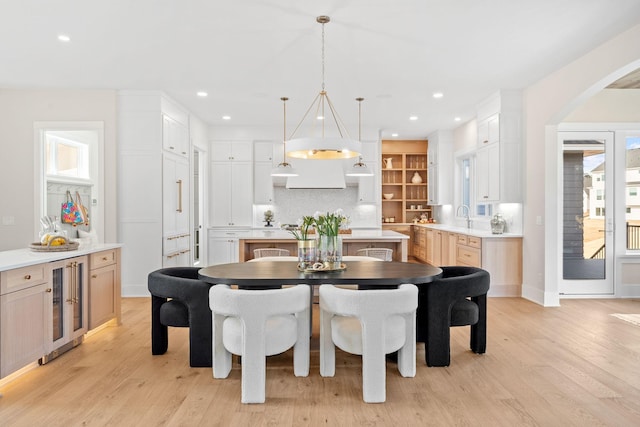 dining room with beverage cooler, light wood-style flooring, recessed lighting, arched walkways, and baseboards