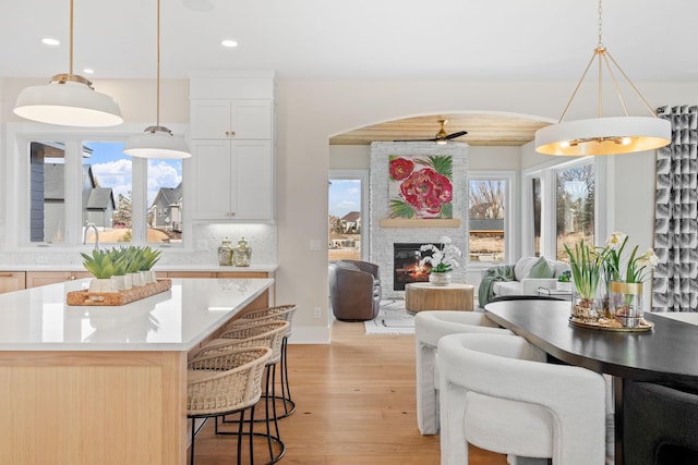 dining area with recessed lighting, a fireplace, light wood-style floors, arched walkways, and a ceiling fan