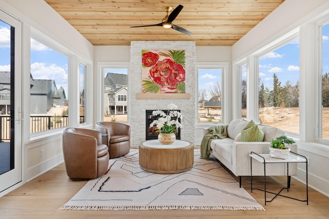 sunroom with lofted ceiling, a brick fireplace, wood ceiling, and ceiling fan