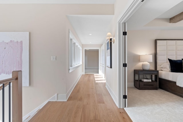 corridor with light wood-type flooring and baseboards