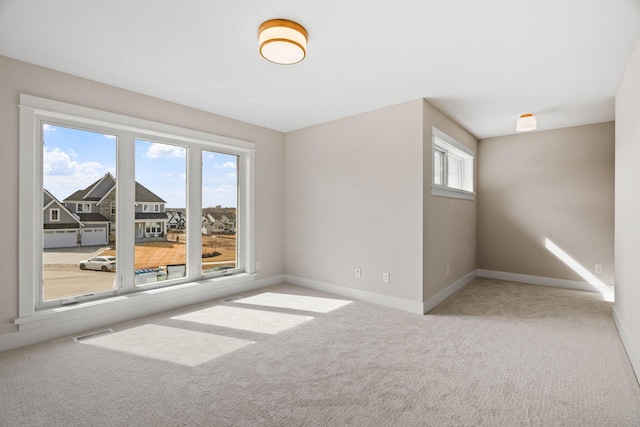 carpeted spare room with visible vents and baseboards