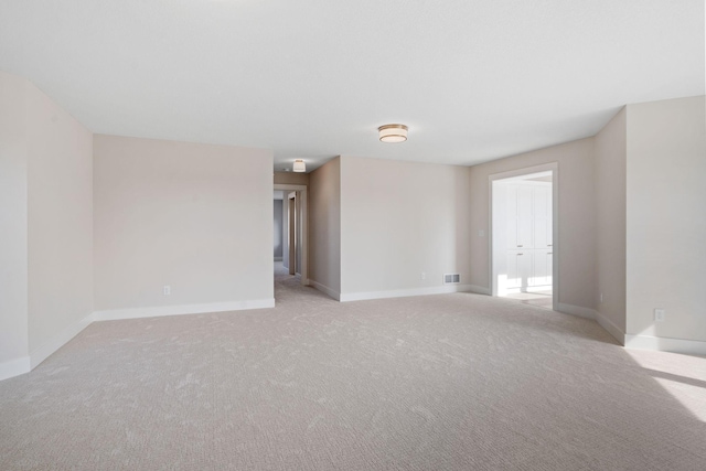 empty room featuring visible vents, baseboards, and light carpet