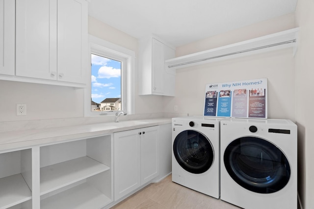 washroom with a sink, cabinet space, and washer and dryer