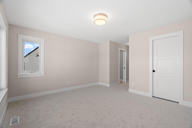 carpeted empty room featuring baseboards and visible vents