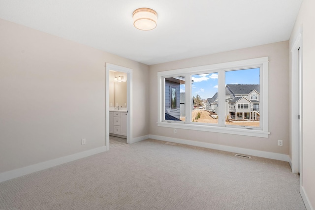 empty room featuring baseboards, visible vents, and light carpet