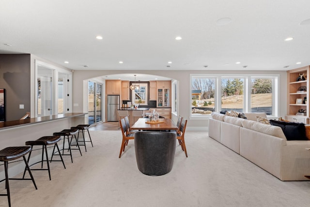 dining space featuring arched walkways, recessed lighting, and light carpet