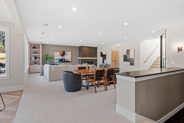 living room featuring recessed lighting, baseboards, a lit fireplace, and stairs