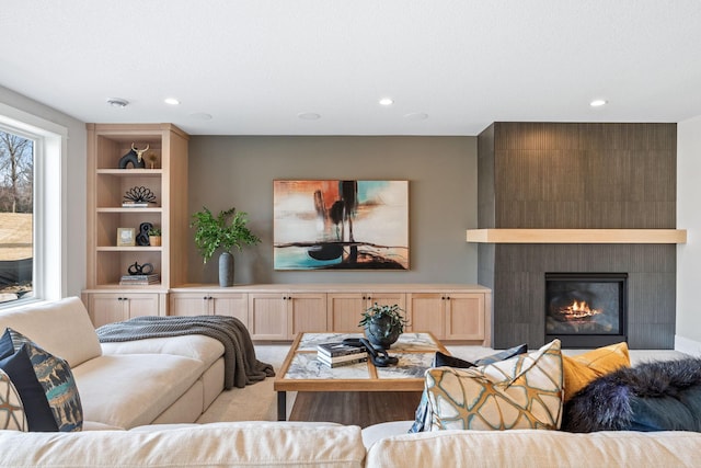 living room with built in features, recessed lighting, light colored carpet, and a large fireplace