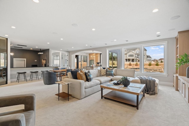 living room featuring recessed lighting, arched walkways, and light colored carpet