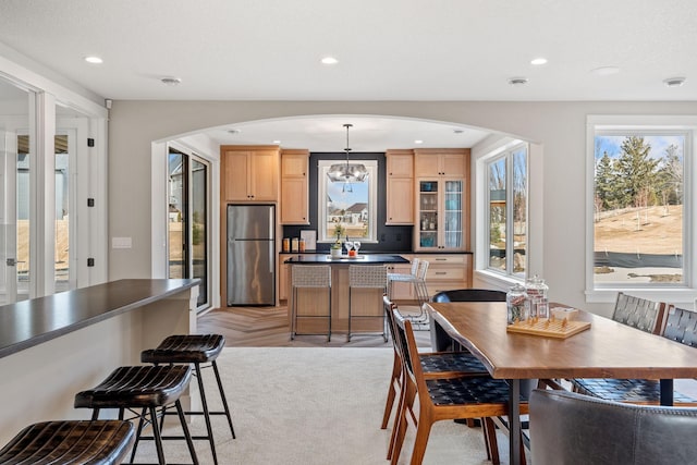 dining area with arched walkways, a chandelier, recessed lighting, and light colored carpet