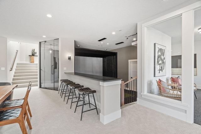 kitchen featuring recessed lighting, a breakfast bar, and carpet