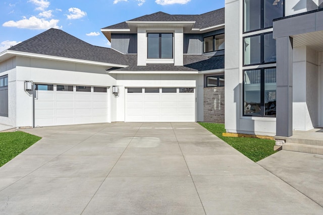 view of front of house featuring a shingled roof, driveway, and stucco siding