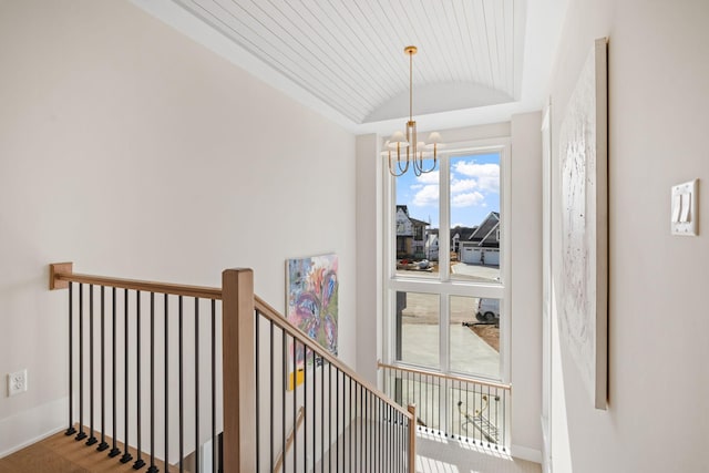 hallway featuring lofted ceiling, a chandelier, an upstairs landing, baseboards, and wood finished floors