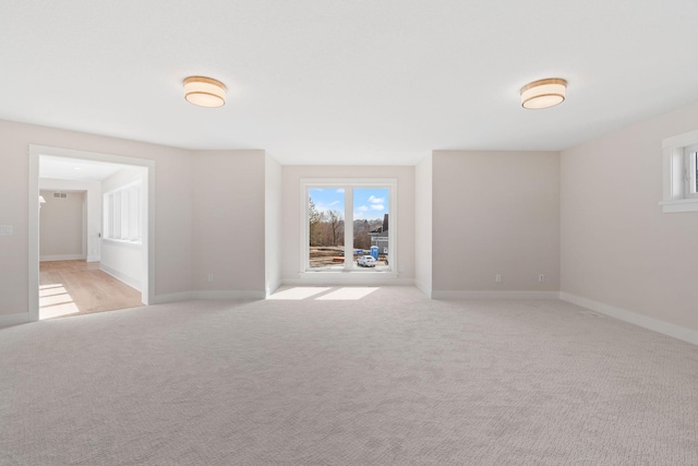 spare room featuring light carpet and baseboards