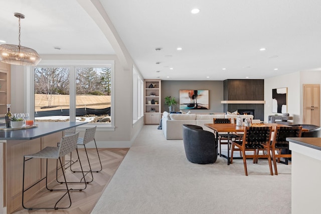 dining area featuring a large fireplace, recessed lighting, baseboards, arched walkways, and a chandelier