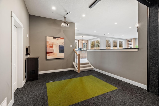 hallway featuring dark colored carpet, baseboards, recessed lighting, and stairs