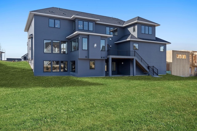 rear view of house featuring stairway, a lawn, and a wooden deck