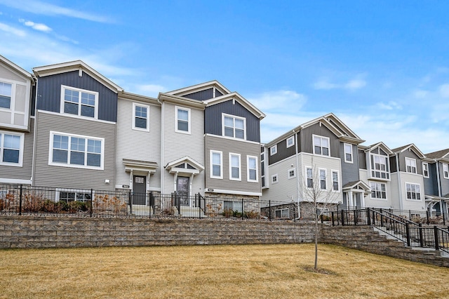 view of property with board and batten siding, a residential view, a front yard, and fence