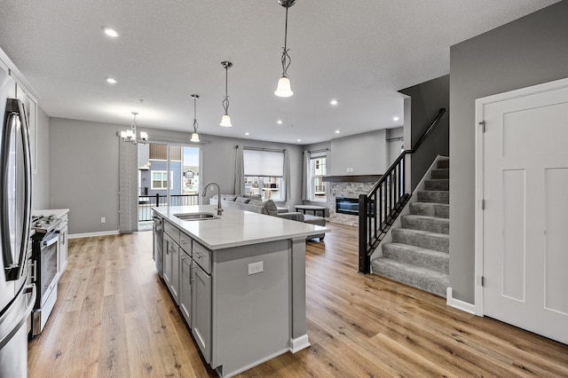 kitchen featuring a stone fireplace, a sink, light wood finished floors, light countertops, and gray cabinetry