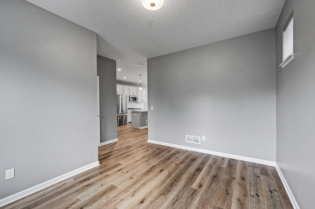 interior space with baseboards, light wood finished floors, visible vents, and recessed lighting