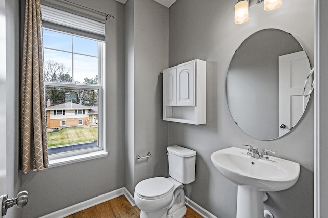 bathroom featuring baseboards, toilet, wood finished floors, and a sink