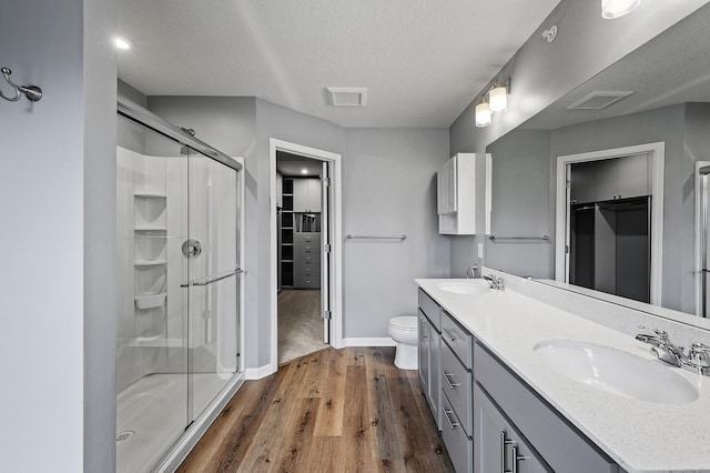 bathroom featuring baseboards, wood finished floors, a sink, and a stall shower