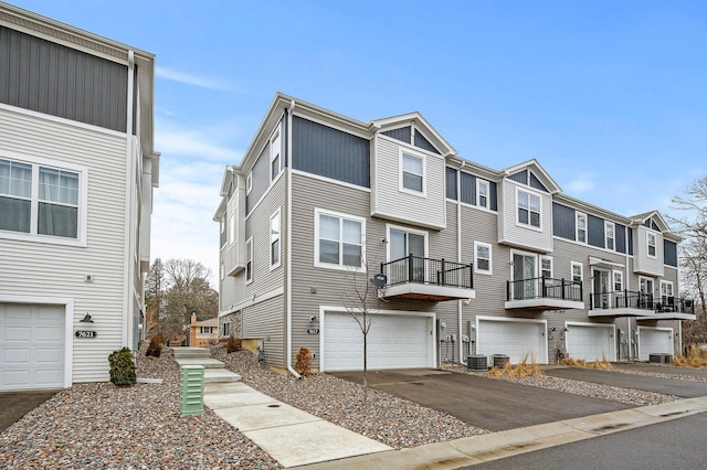 townhome / multi-family property featuring a garage, a residential view, cooling unit, and driveway