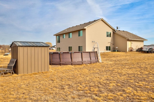 rear view of property with an outbuilding, a storage unit, central AC, and fence