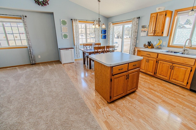 kitchen with a center island, pendant lighting, light countertops, vaulted ceiling, and a sink