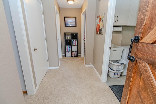 hallway with baseboards and light carpet