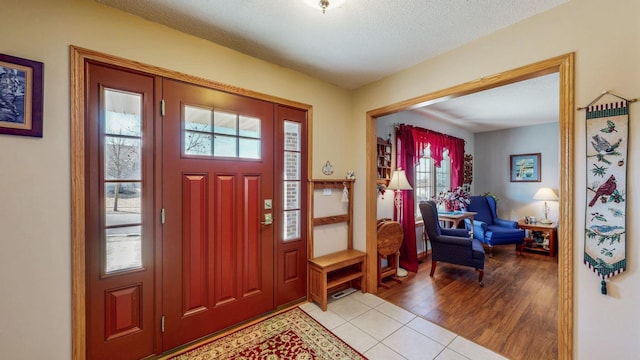 entryway with light wood-style floors and a textured ceiling