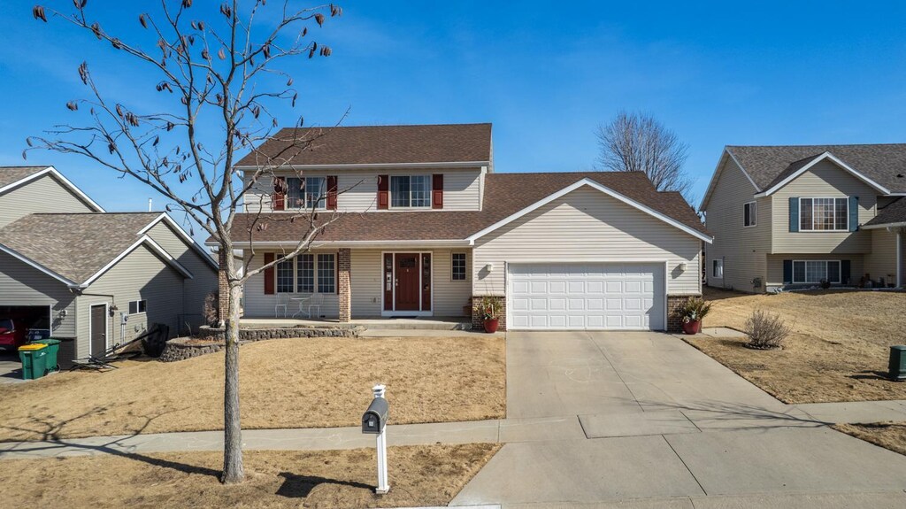 traditional-style house with a porch, a garage, and driveway