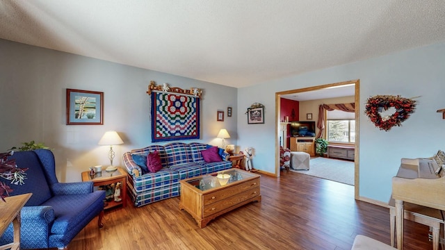 living room featuring a textured ceiling, baseboards, and wood finished floors