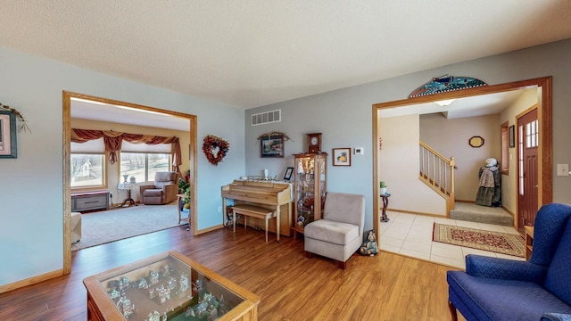 living room featuring stairway, wood finished floors, visible vents, and a textured ceiling