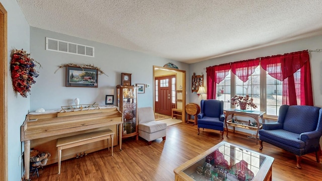 living room with wood finished floors, visible vents, and a textured ceiling