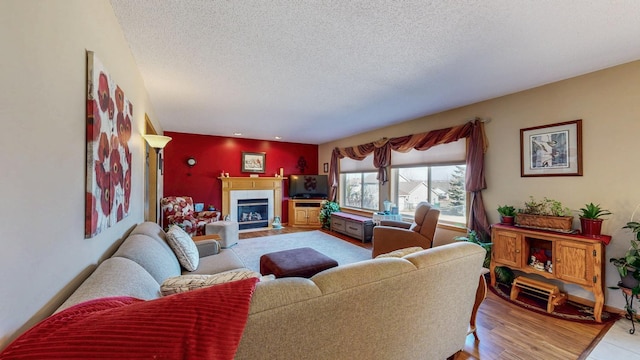 living area featuring baseboards, a textured ceiling, wood finished floors, and a tiled fireplace