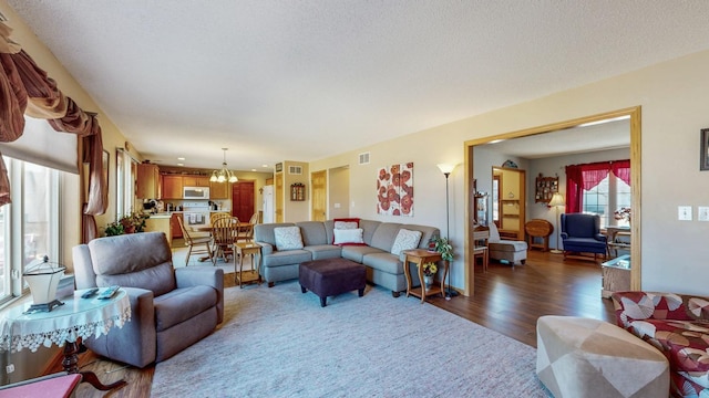 living room with dark wood finished floors, a notable chandelier, visible vents, and a textured ceiling