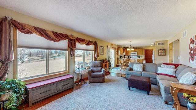 living room with a notable chandelier, visible vents, and a textured ceiling