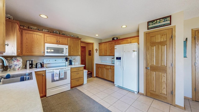 kitchen with white appliances, light tile patterned flooring, recessed lighting, a sink, and light countertops