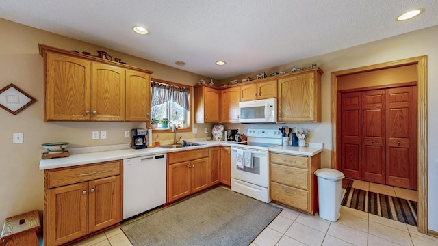 kitchen featuring light countertops, light tile patterned floors, recessed lighting, white appliances, and a sink